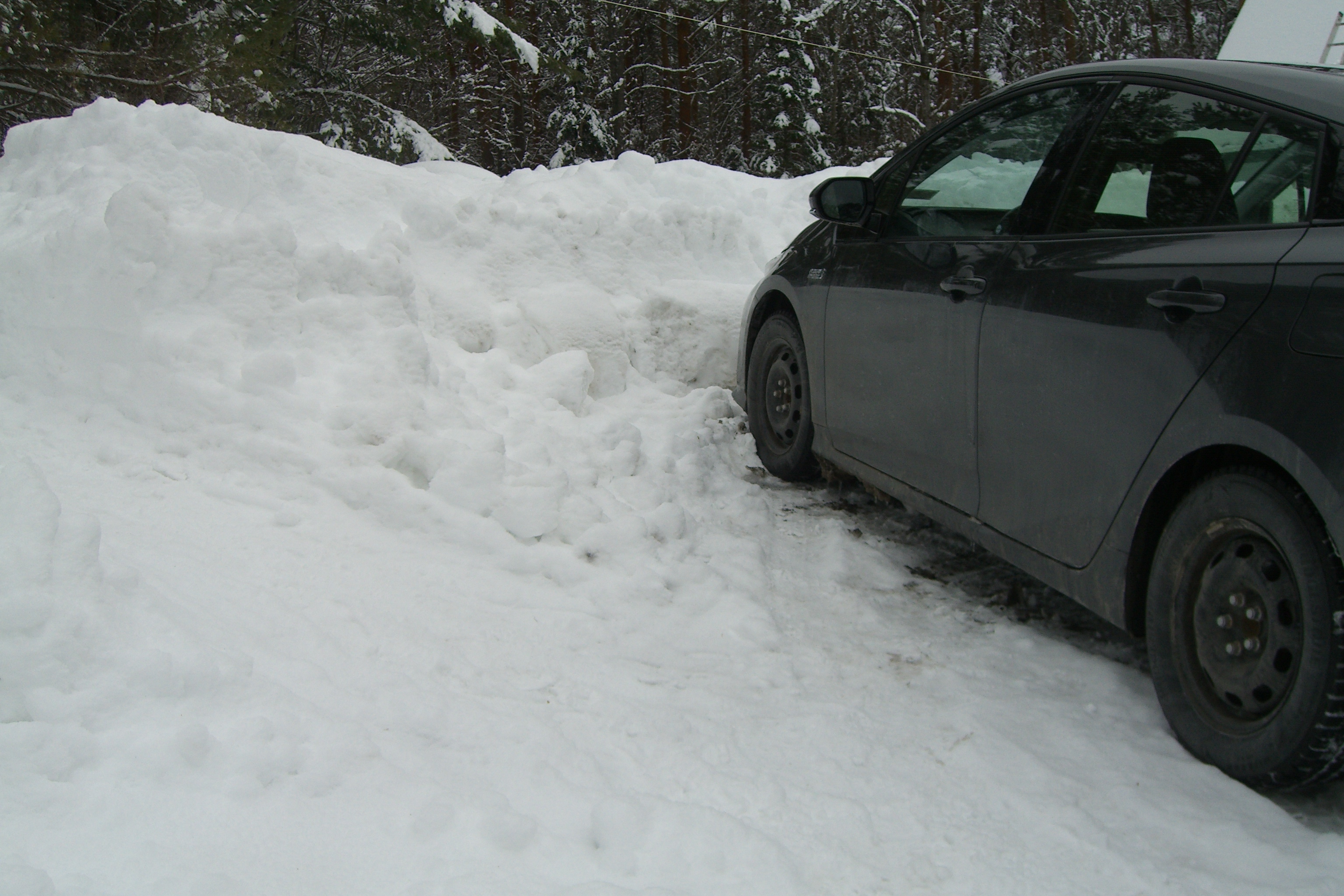 Car buried under a massive snow pile