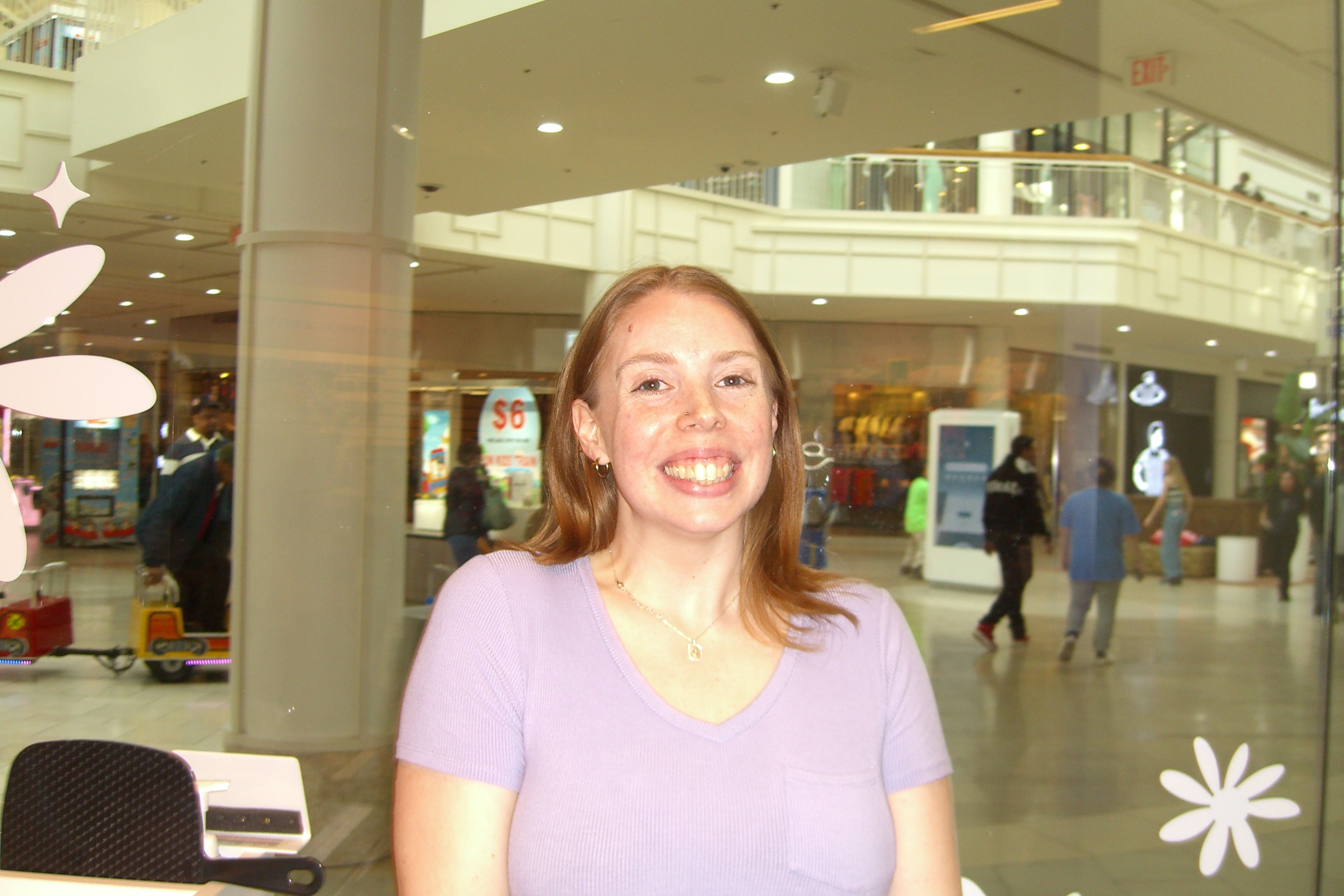 Woman in lavender top smiling at the mall