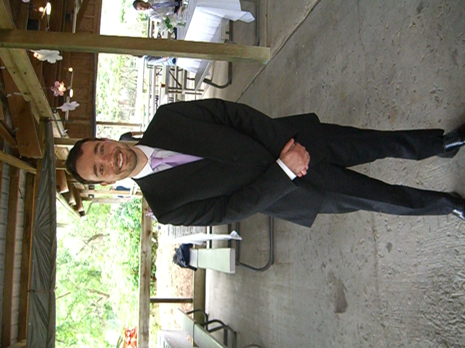Man in dark suit and lavender tie at a formal outdoor venue